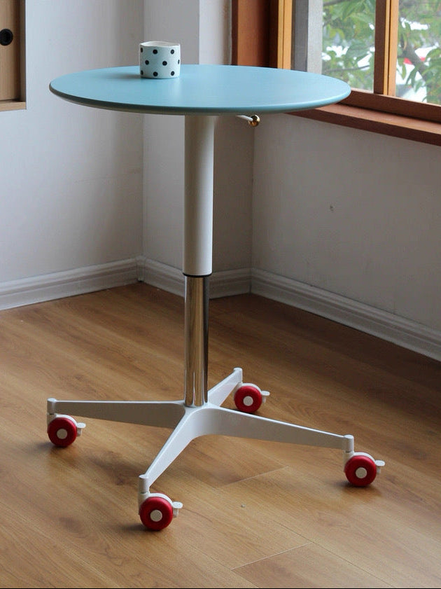 Small round table with wheels in a room with a window and wooden floor.