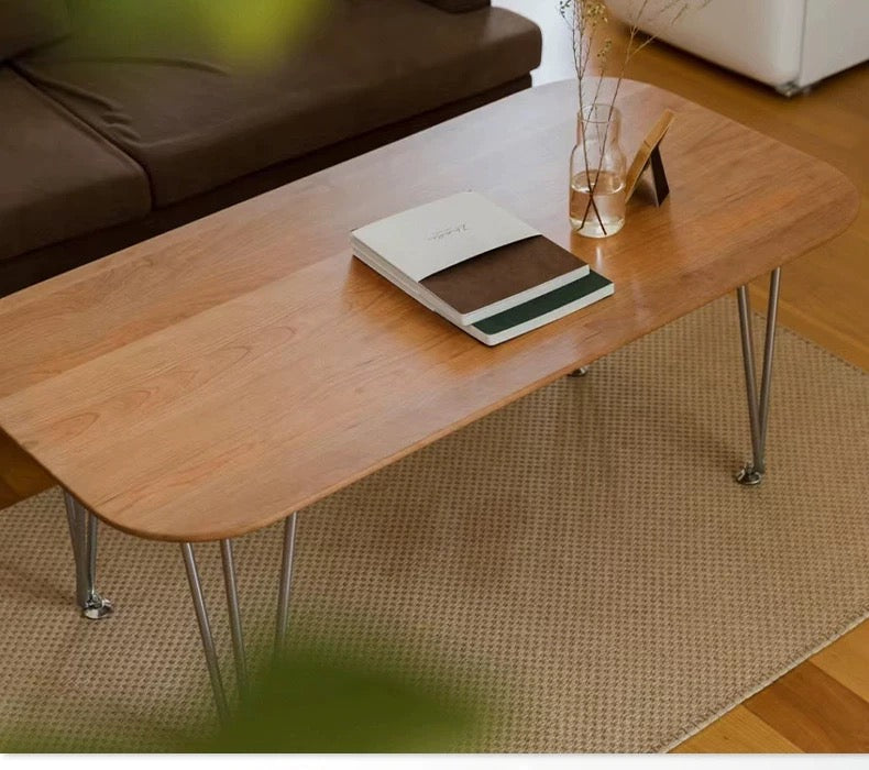 Wooden coffee table with a book and decorative items in a living room setting.