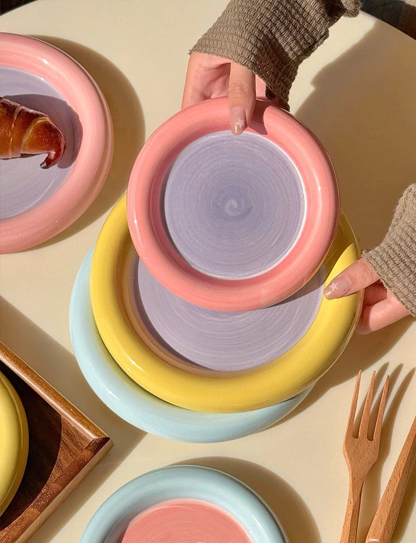 Colorful ceramic bowls stacked on a light surface with wooden utensils.