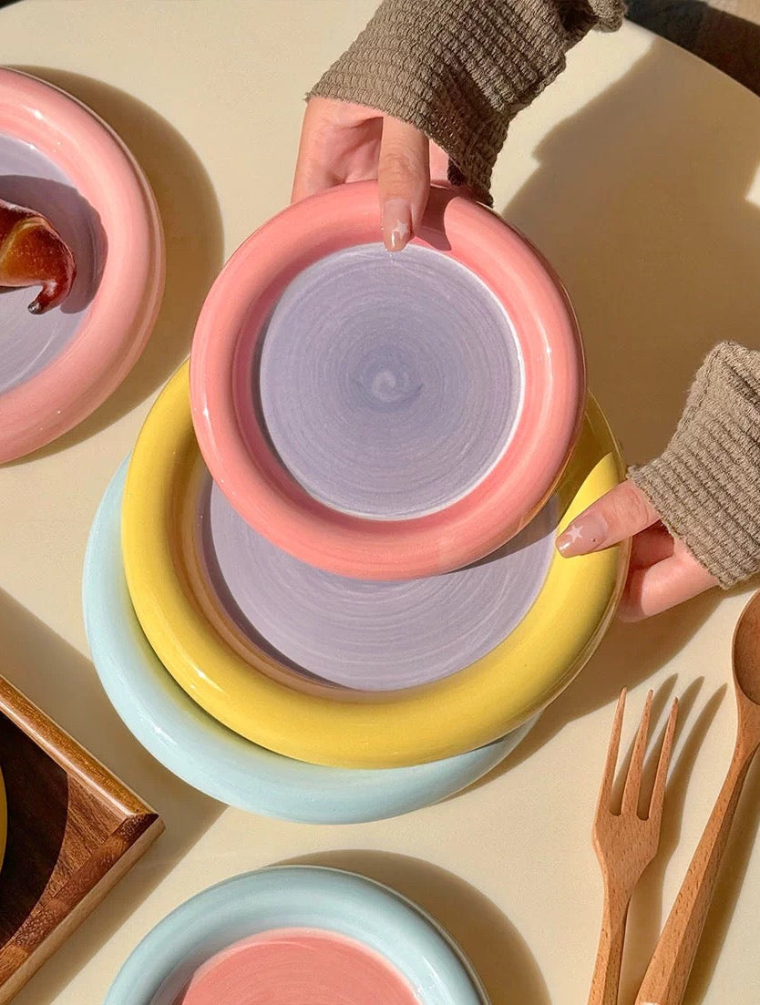 Colorful ceramic bowls stacked on a light surface with wooden utensils.