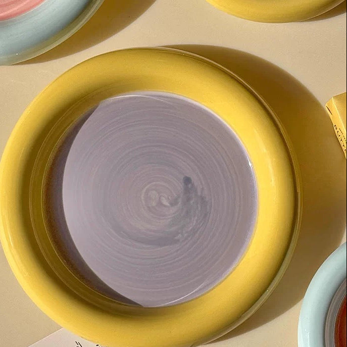 Yellow ceramic plate with purple interior on a beige surface