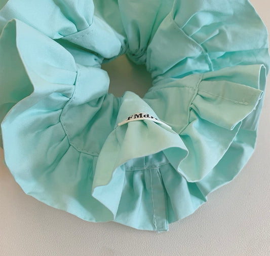 Light blue satin hair scrunchie on a light background
