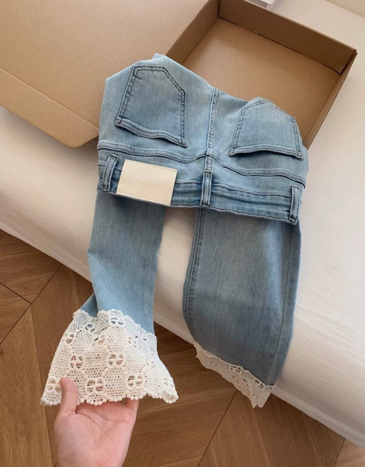 Light blue jeans with lace trim held in front of a cardboard box.