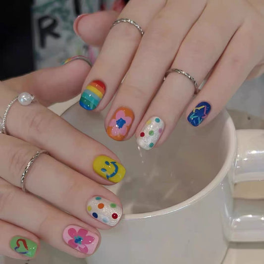 Colorful nail art on a hand with a white mug in the background