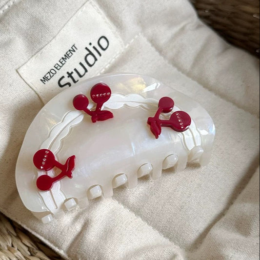 Hair clip with red decorative elements on a beige fabric background