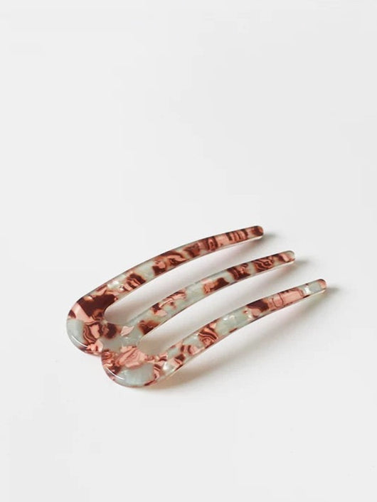 Marbled hair comb on a white background with '' branding.