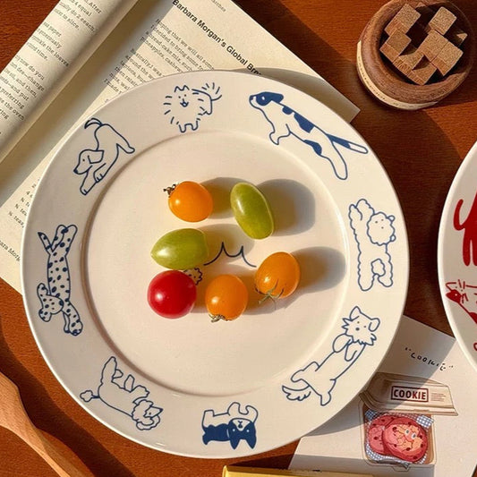Decorative plate with animal illustrations on a wooden surface with books and snacks.