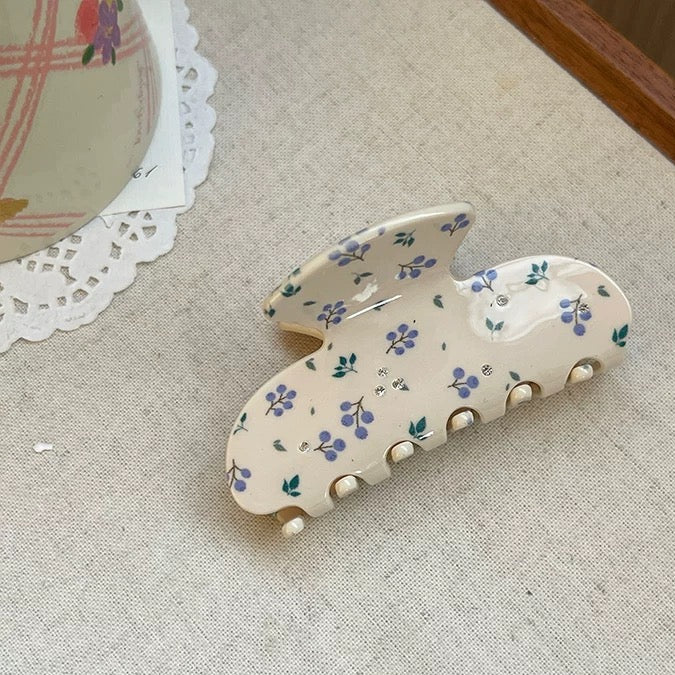 Floral-patterned hair clip on a textured fabric background