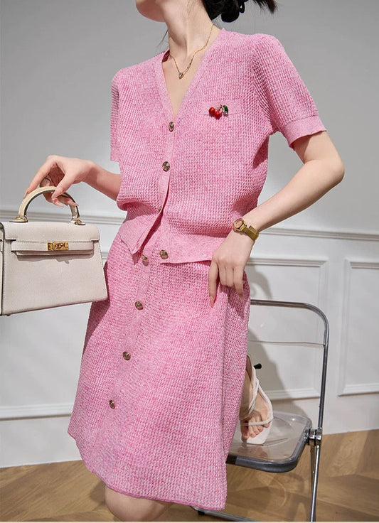 Woman wearing a pink outfit with a matching handbag in an indoor setting