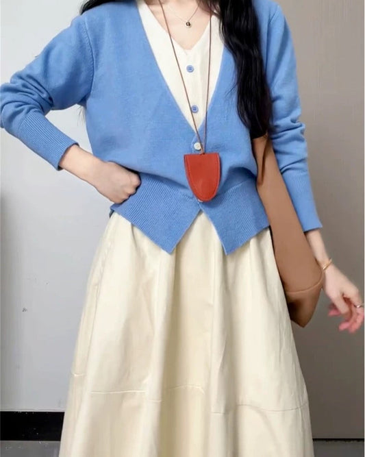 Person wearing a blue cardigan and beige skirt with a cartoon pig head.