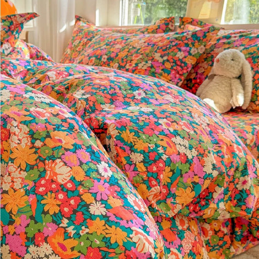 Colorful floral bedding set with a teddy bear on a bed.