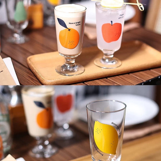 Two glasses with fruit designs on a wooden tray