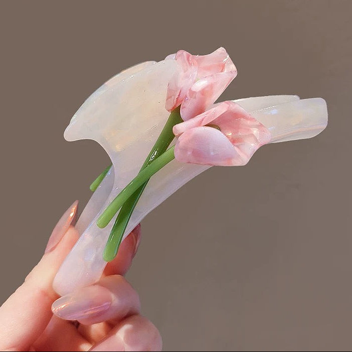 Hair clip with pink floral design held by a hand against a brown background, featuring the brand 'MOYI'.